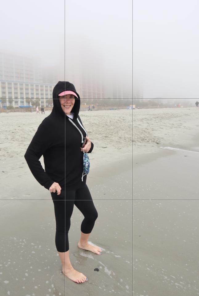 Woman on the beach wearing a hoodie. With fog. Posed and showing Grid Lines on photo.