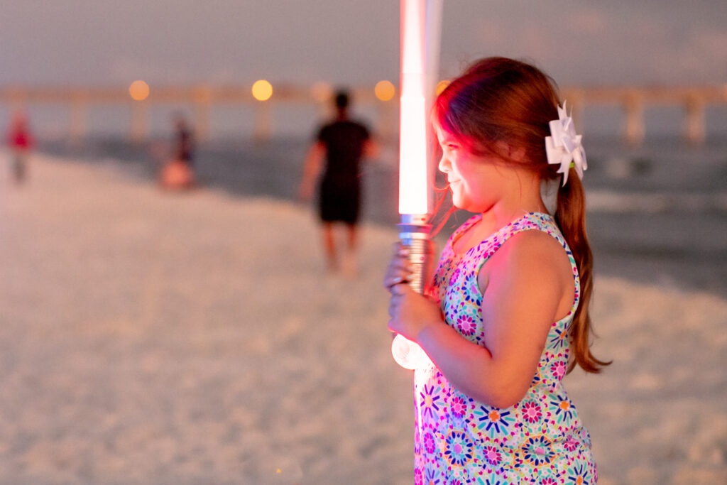 Young girl on the beach holding a light saber and without the Rule of Thirds grid as finished photo. One of the technique for how to make your family photos and videos look AMAZING