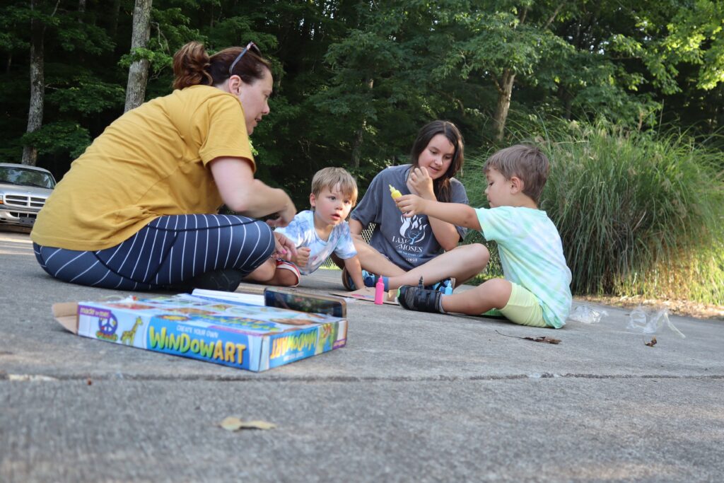 Photo of woman and teen with toddlers playing with sidewalk chalk. This is an example using props and activities in photos. 