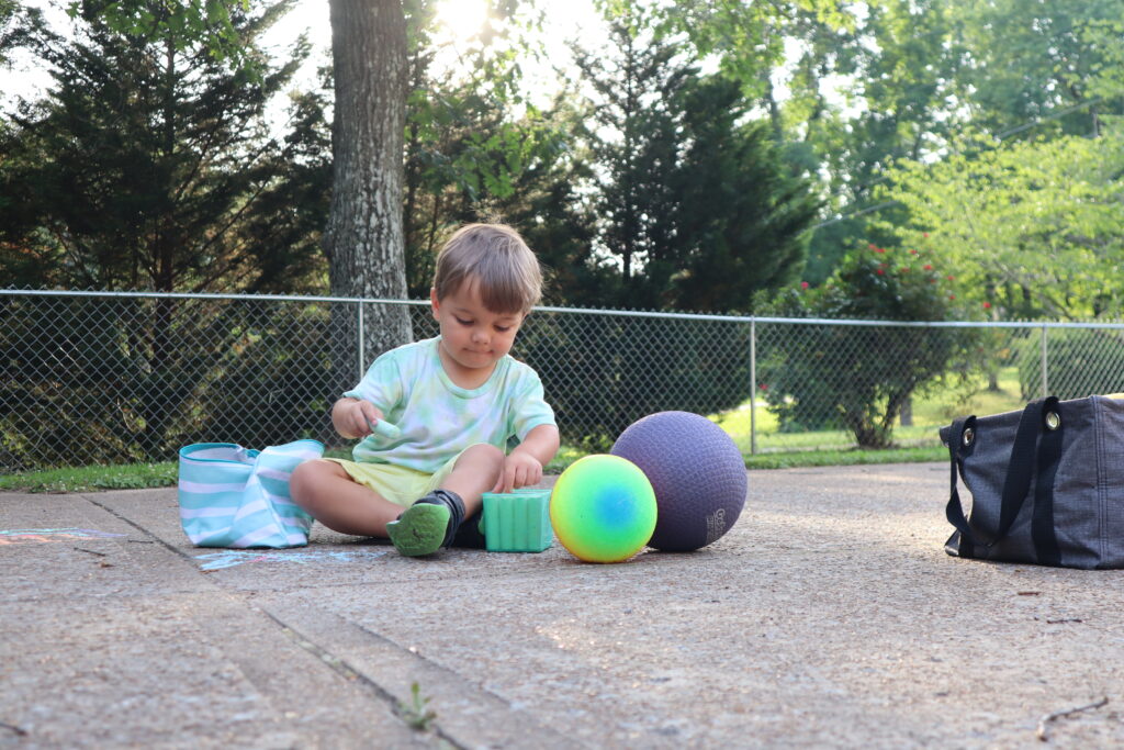 This a photo of a young boy playing with sidewalk chalk in a driveway. This is an example of a candid photo using Rule of Thirds and changing angles.