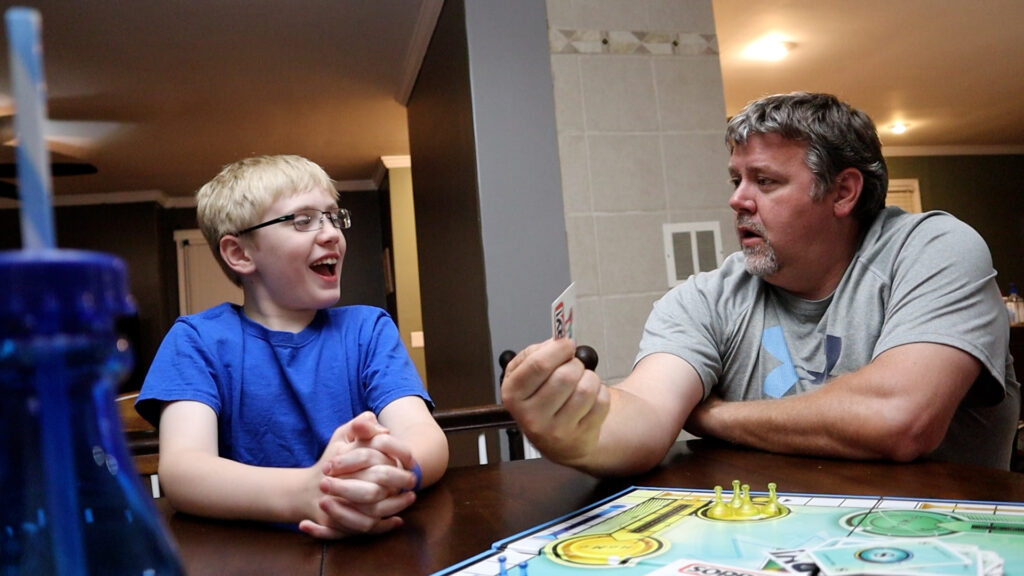 Photo of a man and young boy playing a board game. This is an example using props and activities in photos. 