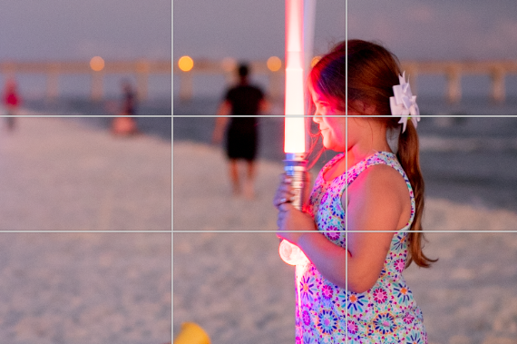 Young girl on the beach holding a light saber and the Rule of Thirds grid as on overlay. One of the technique for how to make your family photos and videos look AMAZING